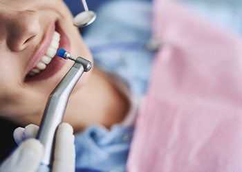 Patient smiling about to have teeth professionally cleaned with special brush and mirror