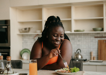 Woman smiling while enjoying meal at home