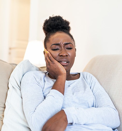 Woman on couch experiencing toothache