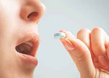 Closeup of woman holding pill to her mouth