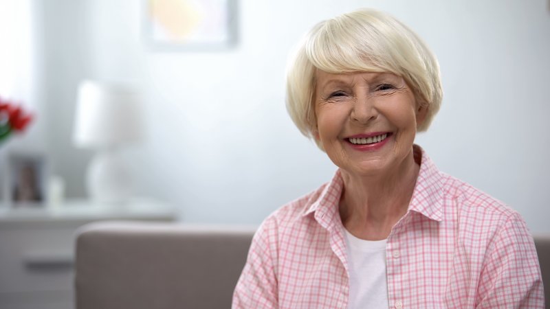 older lady in pink blouse smiling with dental implants