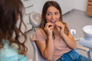 Woman in dentist’s chair putting in clear aligner.
